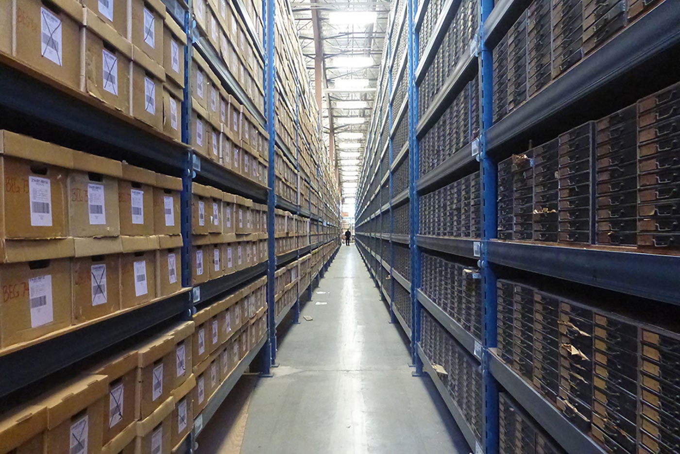 cardboard file boxes stacked on blue shelves in warehouse