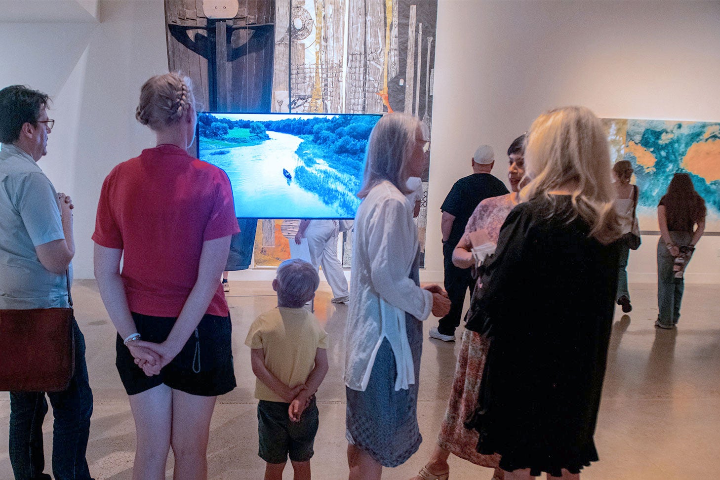 people looking at video on screen in gallery during opening reception