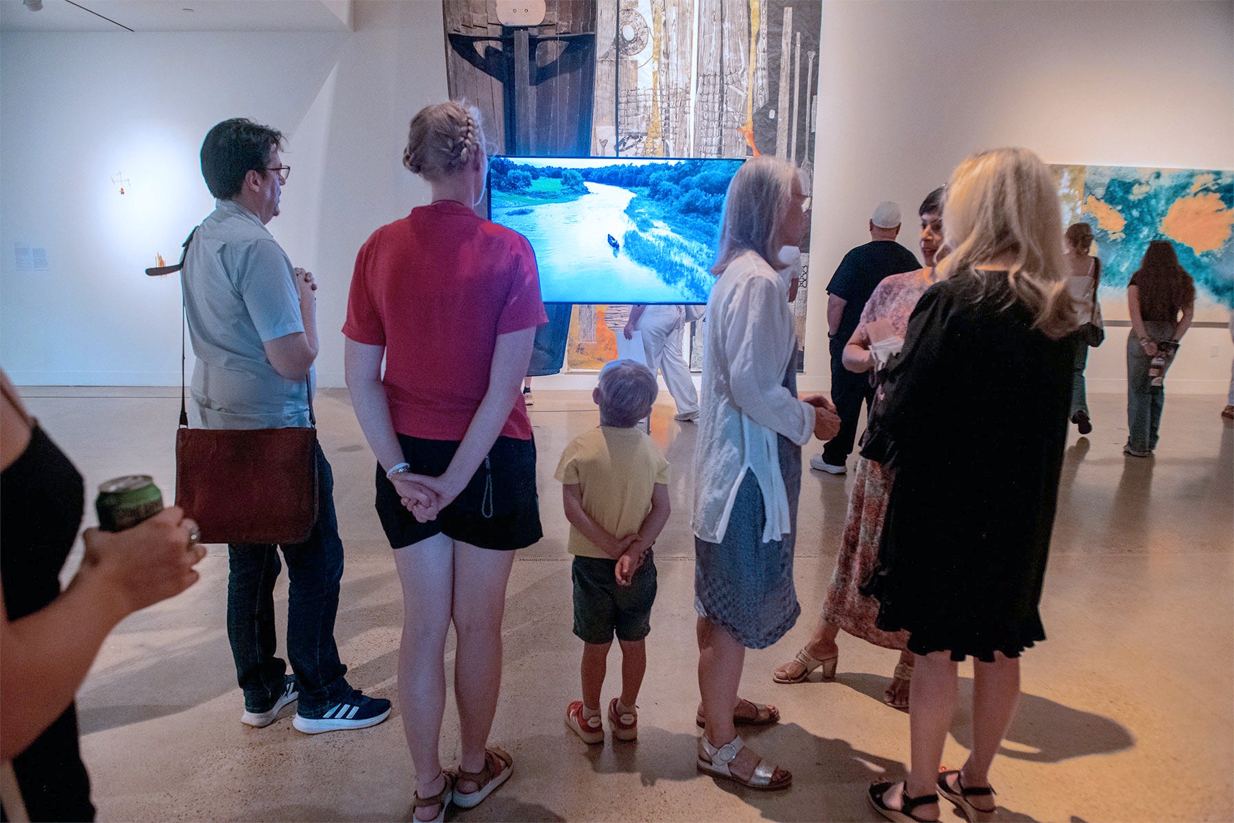 people looking at video on screen in gallery during opening reception