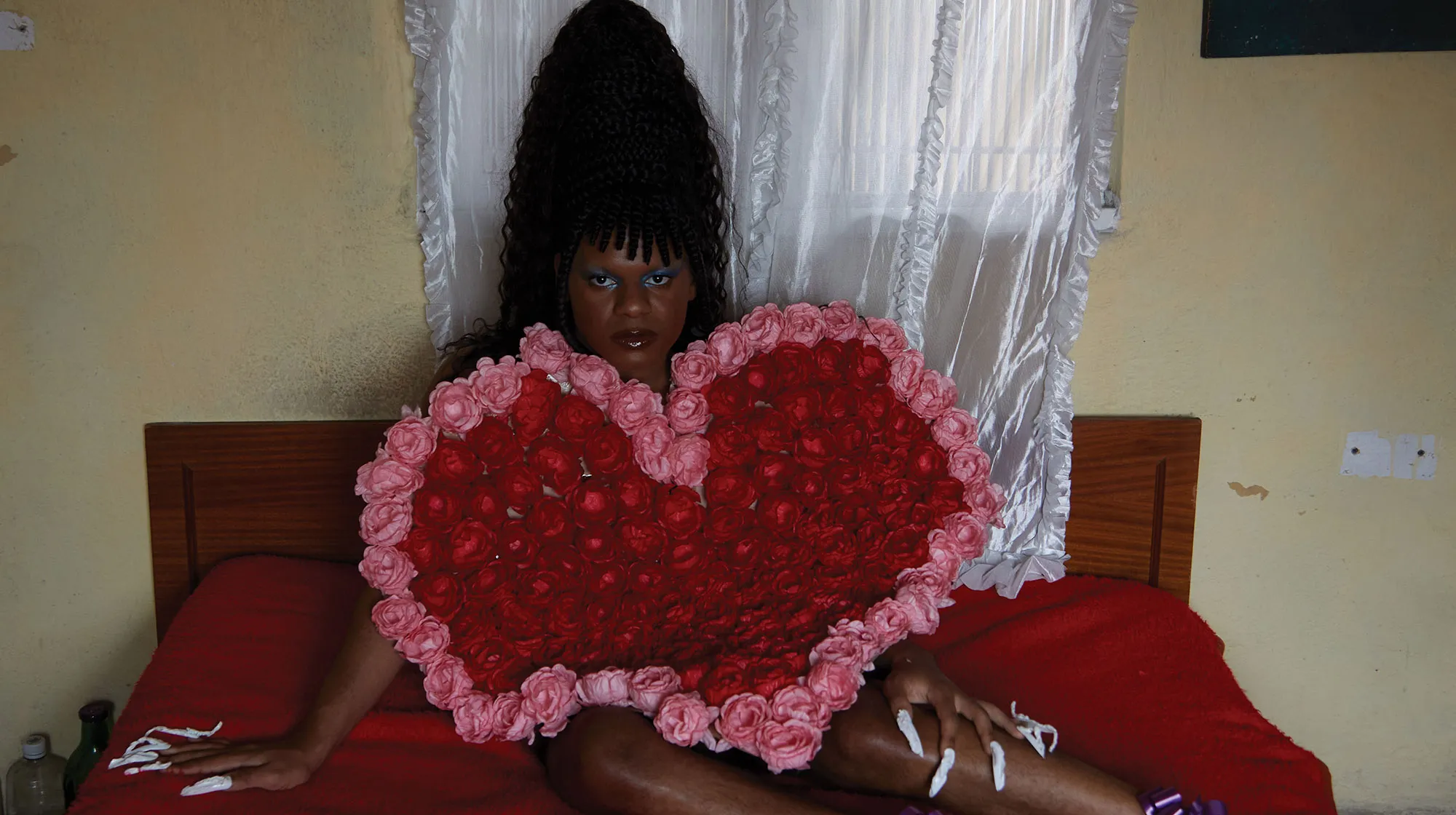 person laying on bed holding red and pink heart piece