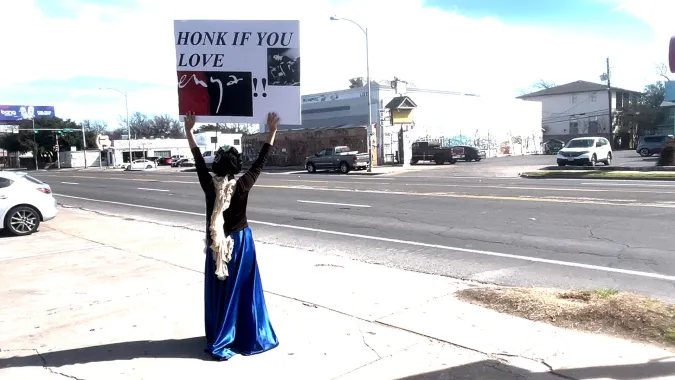 person holding sign on side of street
