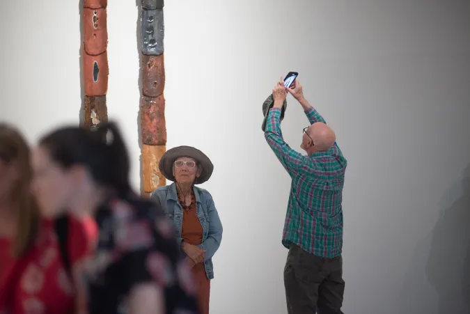 person taking photo of artwork on wall 
