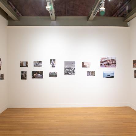 installation image of three gallery walls with small photographs hung in alternating lines