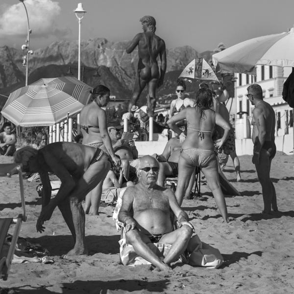 people on beach with Italian sculpture in background