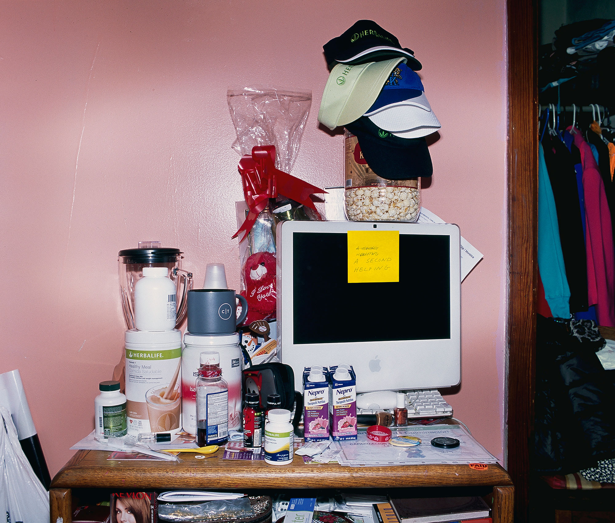 small table piled with objects including old computer, blender, herbalife and valentine's basket