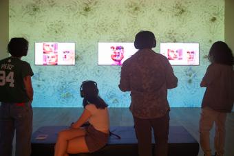 four people watching screen-based artwork in gallery