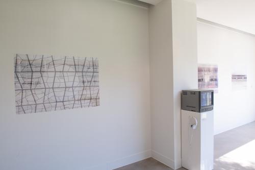 brightly lit gallery wall featuring a double exposed photograph and a small TV featuring video work