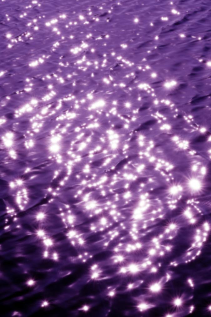 surface of water with ripples and cast in purple hue