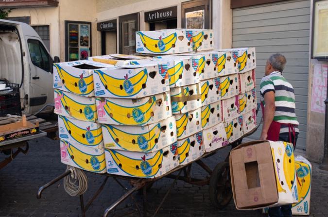 person stacking large box printed with yellow banana graphic